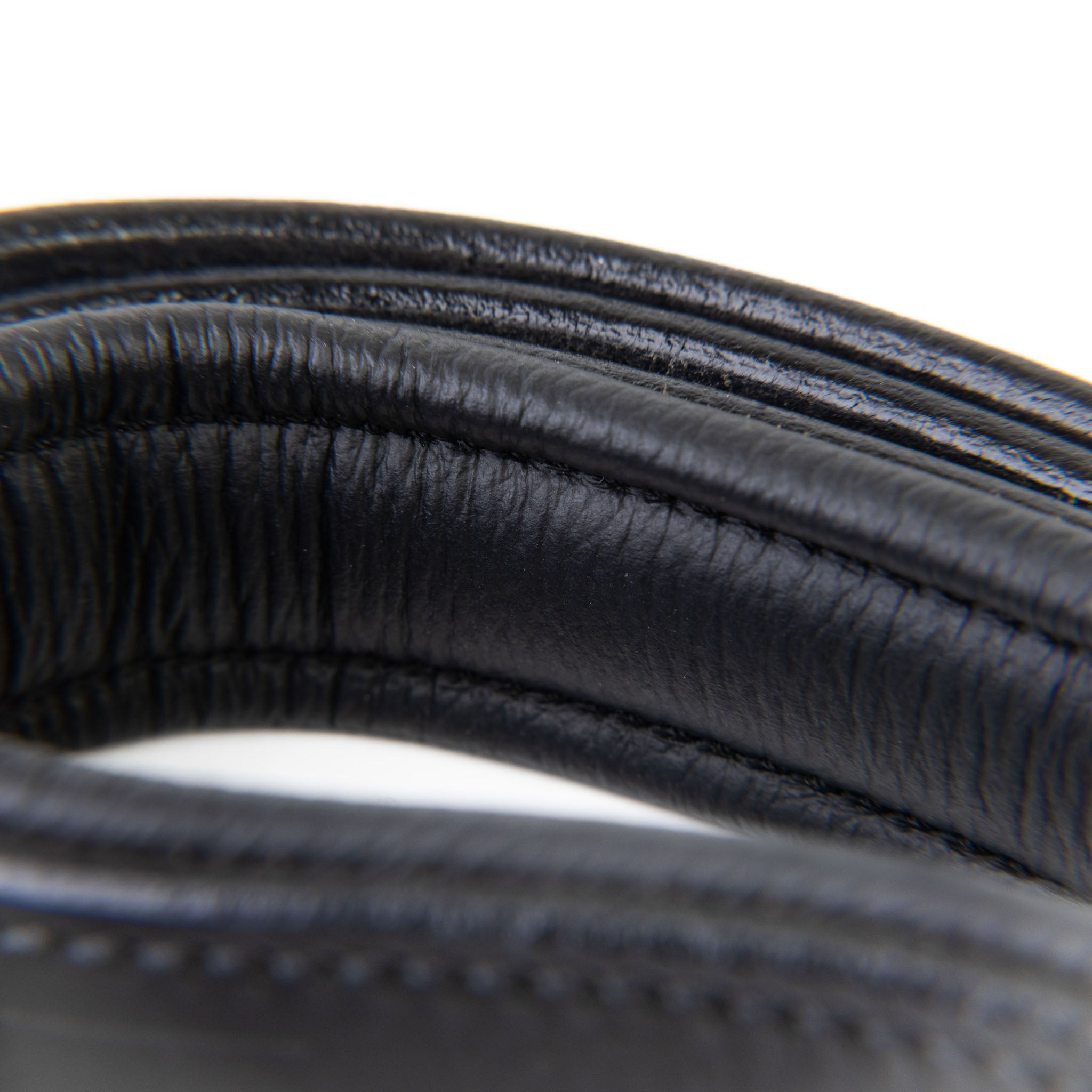 Close-up of a coiled black rubber hose on a white background