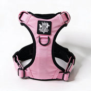 Pink and black dog harness with a central logo patch, photographed on a clean white background.